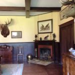 Colour photo of a room with moose head , elk head, fireplace