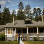 Colour photo of man and woman standing and hugging in front of heritage manor house