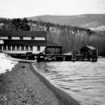 B&W photo of a building and wharf, launch boat in foreground